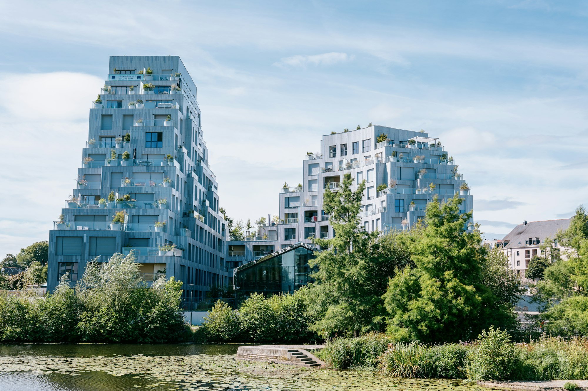 Deux immeubles neufs en gradins, couverts de terrasses plantées, au bord de l’eau
