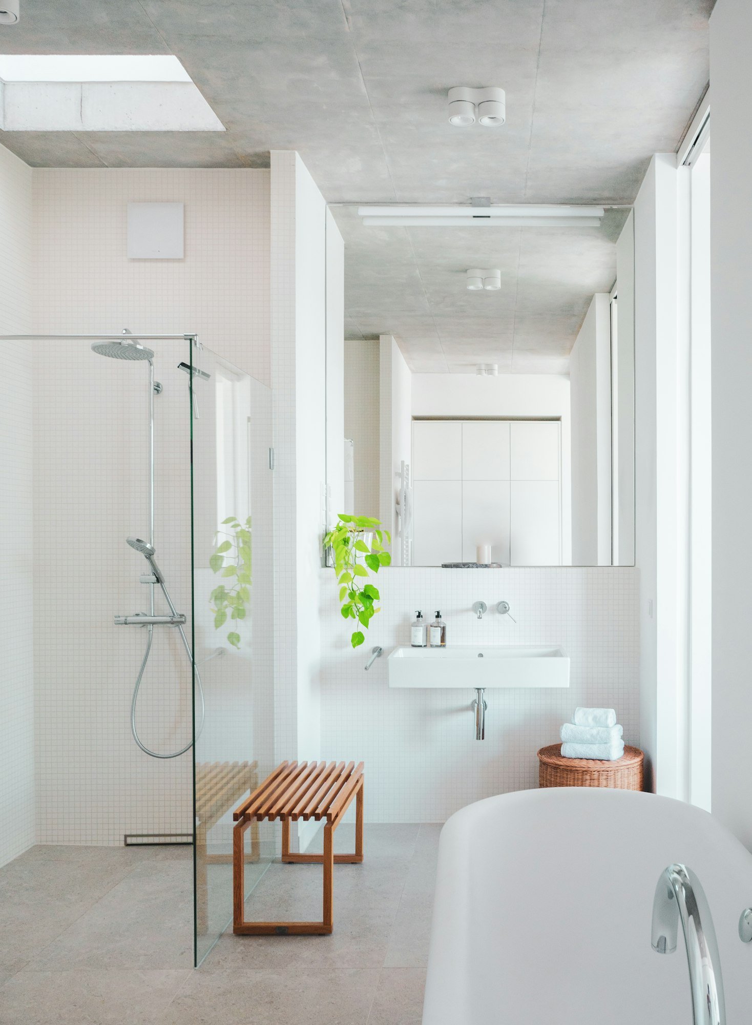 Une salle de bains blanche avec baignoire, douche à l’italienne et vasque suspendue